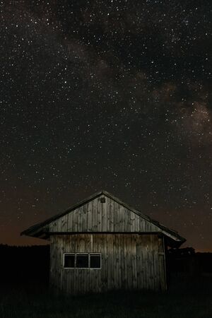 Small old wooden house on the background of the starry night. Starry night. Stars in the nightの写真素材