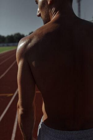 Rear view of shirtless muscular man. Sportsman. Strong athletic man