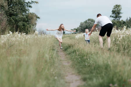 Mom, dad and their little son having fun while resting on nature. Young happy family. Mother, father and little sonの写真素材
