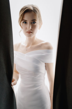 Medium shot portrait of a beautiful young lady in white looking sensually at the camera. High quality photoの写真素材