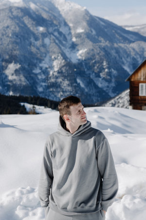 Portrait of a young guy against the backdrop of snow-capped mountains. Winter holidays, active lifestyle, skiing and hiking. High quality photoの写真素材