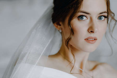 Close-up portrait of a beautiful bride with blue eyes looking at the camera.