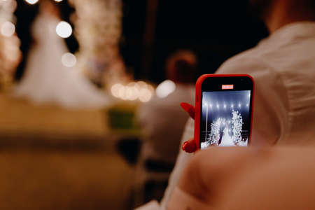 People using a smartphone take pictures during the wedding evening ceremony