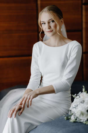 Beautiful bride in a dress sitting on the bed in her bedroom.の写真素材