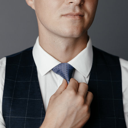 Young businessman tightens his tie close upの写真素材