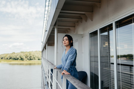 Woman in the city on the balcony. Girl at the window of his apartment in the city. Lady on the background of the city river.の写真素材