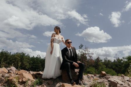 Romantic wedding couple posing on top of mountains at sunset with amazing view. Beautiful newlyweds on their wedding dayの写真素材