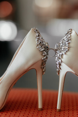 Wedding ring between cream heels of the bride, decorated with diamonds. Vertical photoの写真素材