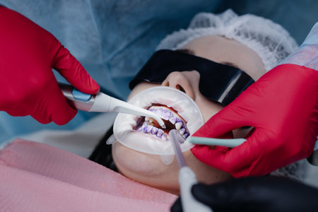 Top view of the process of brushing the patients teeth. Brushing teeth with water jet and saliva remover. Retractor cheeks on the lips. The concept of professional oral hygiene.の写真素材