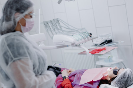 A female dentist in a dental office prepares a patient for treatment.の写真素材