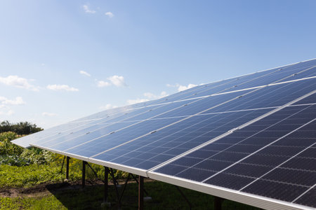 Powerful solar panels in a field against a blue cloudy sky background.の写真素材