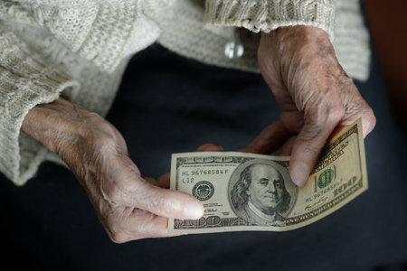 Female hands hold one hundred US dollars. Pension, poverty, social problems and the topic of old...