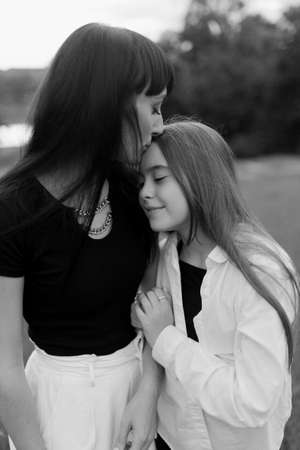 Mother kisses and hugs her little daughter in the park. Happy family concept. Black and white photoの写真素材
