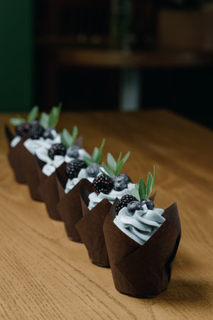 Chocolate cupcakes with berries in a row on the table. Side viewの写真素材