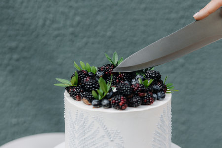 Female cutting chocolate cake with berries on a wooden tableの写真素材
