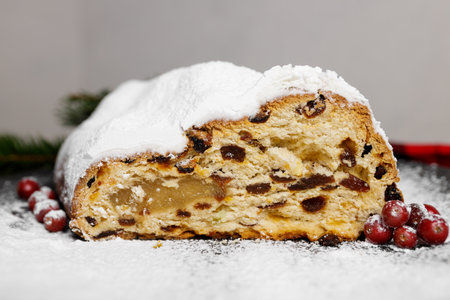 Traditional German Christmas stollen with fruit and nuts cut on a black plate