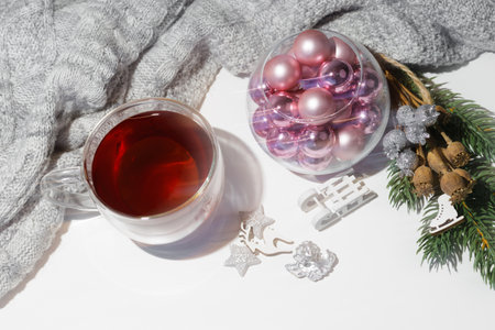 Christmas arrangement of pink balls for the Christmas tree, cups of black tea, decorated with a knitted gray sweater on a white table. Preparation for the holidays. Lubrication effectの写真素材