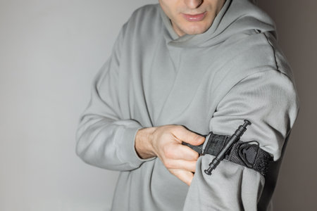 A person puts a tourniquet on his arm to prevent bleeding during first aid. Training in tactical medicine. Combat application harnessの写真素材