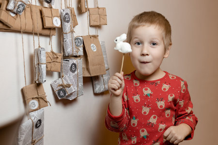 Boy with toy 2023 symbol rabbit standing near handmade Christmas advent calendar