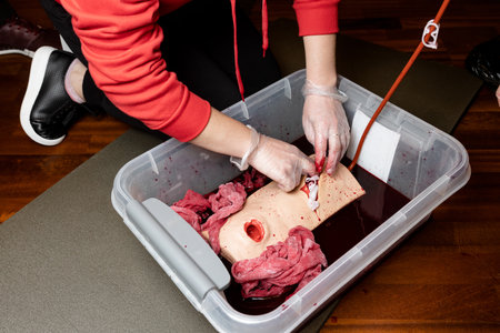 A civilian practices on a wounded dummy to stop the bleeding. Hands close up