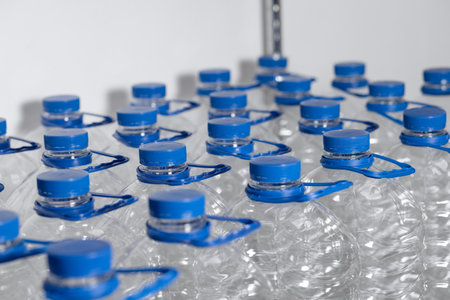 Many empty water bottles with lids and handles are lined up in a display case.の写真素材