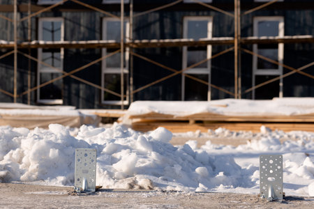 Close-up of metal fasteners in the foundation of a modular home against the background of a completed modular homeの写真素材