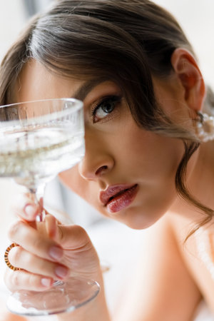 Close-up portrait of a young woman with a glass of champagne near her faceの写真素材