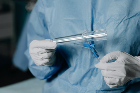 A surgeon in latex gloves and a blue uniform holds a special proctological instrumentの写真素材