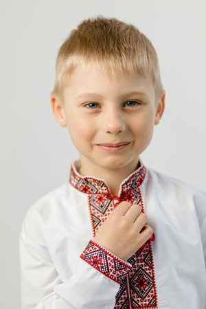 A 6-year-old boy in an embroidered shirt smiles at the camera on a white background. Close upの写真素材