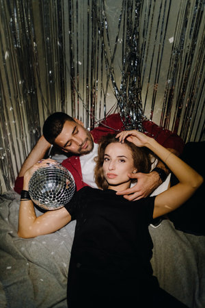Young European couple lying on the floor at home on a gray blanket at homeの写真素材