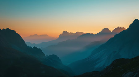 A breathtaking view of a sunrise illuminating the rugged peaks and serene valleys of a mountain range, casting an ethereal glow and intricate shadowsの素材
