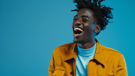 A man with dreadlocks is laughing while wearing a bright yellow jacket. He appears joyful and expressive in his laughter.の素材