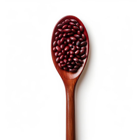 A wooden spoon is heaped with red kidney beans, highlighting the rich color of the legumes against the simple, light background. This setup emphasizes preparation for a meal.の素材