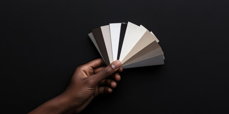A hand gracefully presents a vibrant collection of interior wall paint samples. This captivating moment captures the essence of home decor creativity and design possibilities.の素材