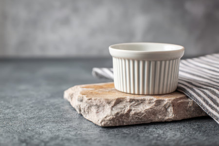 A delicate ramekin rests on a natural stone slab, surrounded by a soft, neutral-toned kitchen. The warm ambiance inspires delicious culinary adventures and cozy gatherings.の素材
