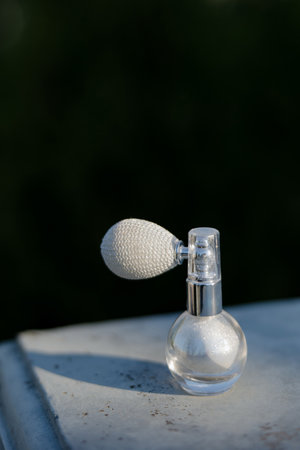 Elegant perfume bottle exuding charm against a blurred outdoor backdropの写真素材