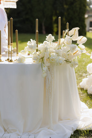 Elegant garden table adorned with white flowers and gold candles for a beautiful spring celebrationの写真素材