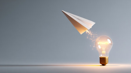 A light bulb hovers as a paper airplane flies away, leaving behind a trail of sparkling magic in a minimalist setting.の素材