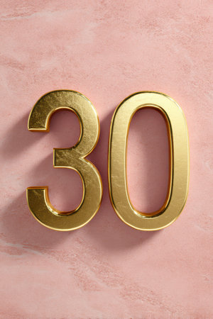 A gleaming golden number 30 stands prominently against a delicate pink backdrop, symbolizing a special celebration or achievement.の素材