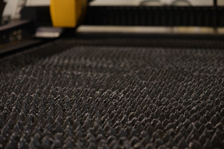 A detailed view of specialized machinery crafting parts, illuminated in a dimly lit, unfinished...