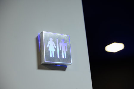 Restroom signs illuminated with blue light add a modern touch to unfinished spaces within a factory environment.の写真素材