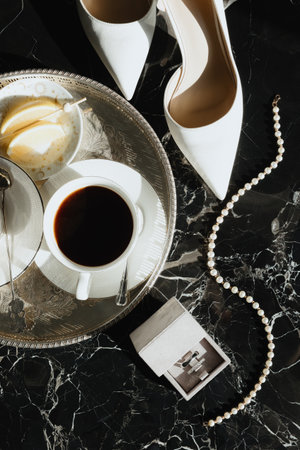 Elegant afternoon tea with coffee, dessert, and chic accessories on a marble trayの写真素材
