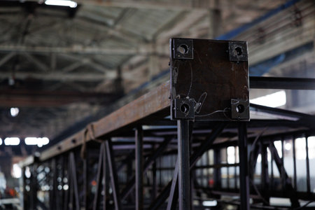 Dark steel beams rise in a large industrial building as light streams through the windows, revealing the artistry of construction.の写真素材