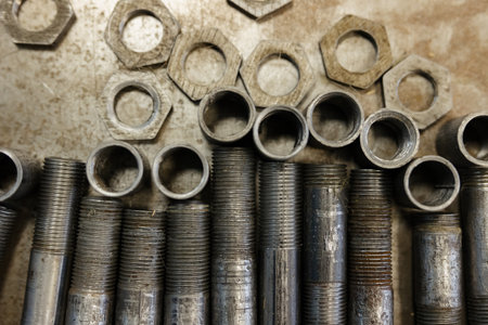 Metal nuts and threaded pipes waiting for assembly in a workshop