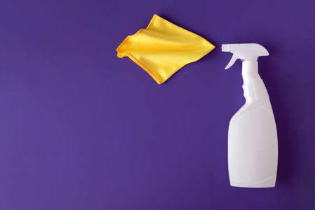 White spray plastic bottle of cleaner antiseptic on a violet paper background with yellow microfiber cloth. Closeup, top view, place text.の写真素材