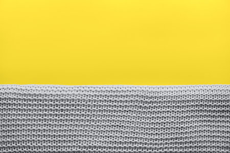 A beautiful knitted gray plaid on solar yellow background. Perfect background color 2021. The trend of the spring and summer season in the fashion design industry. Place for text, blank, copy-space.の写真素材