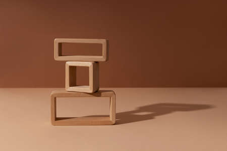 Three wooden square rectangular frames constructor abstract minimal product promotion pedestal with shadow on brown and beige paper background. Natural showcase copy space.の写真素材