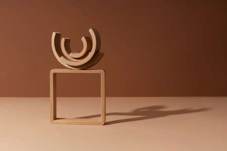 Wooden arches concept balance on a square frame constructor abstract minimal product promotion pedestal with shadow on brown and beige paper background. Natural showcase copy space, wooden semicircle.の写真素材