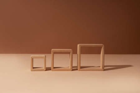 Three wooden square frames abstract minimal product promotion pedestal with shadow on brown and beige paper background. Natural showcase copy space.の写真素材