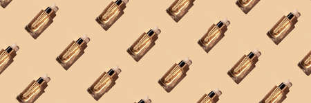 Seamless pattern banner a beautiful transparent bottle cosmetic moisturizing, anti-aging serum oil made from natural ingredients on beige color background in the sun with a beautiful shadow, top view.の写真素材